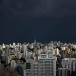 Vista do horizonte urbano de São Paulo sob nuvens escuras de tempestade.