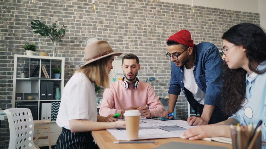 Jovens trabalham juntos em uma sessão de brainstorming em um escritório moderno.