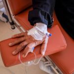 Close de uma mão recebendo quimioterapia por via intravenosa em uma unidade de saúde.