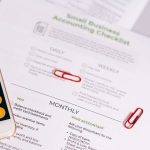 Checklist e calculadora sobre uma mesa, representando a organização das obrigações contábeis de um pequeno negócio