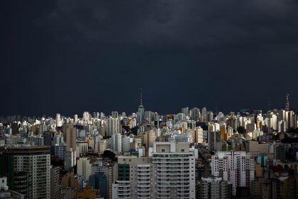 Vista do horizonte urbano de São Paulo sob nuvens escuras de tempestade.